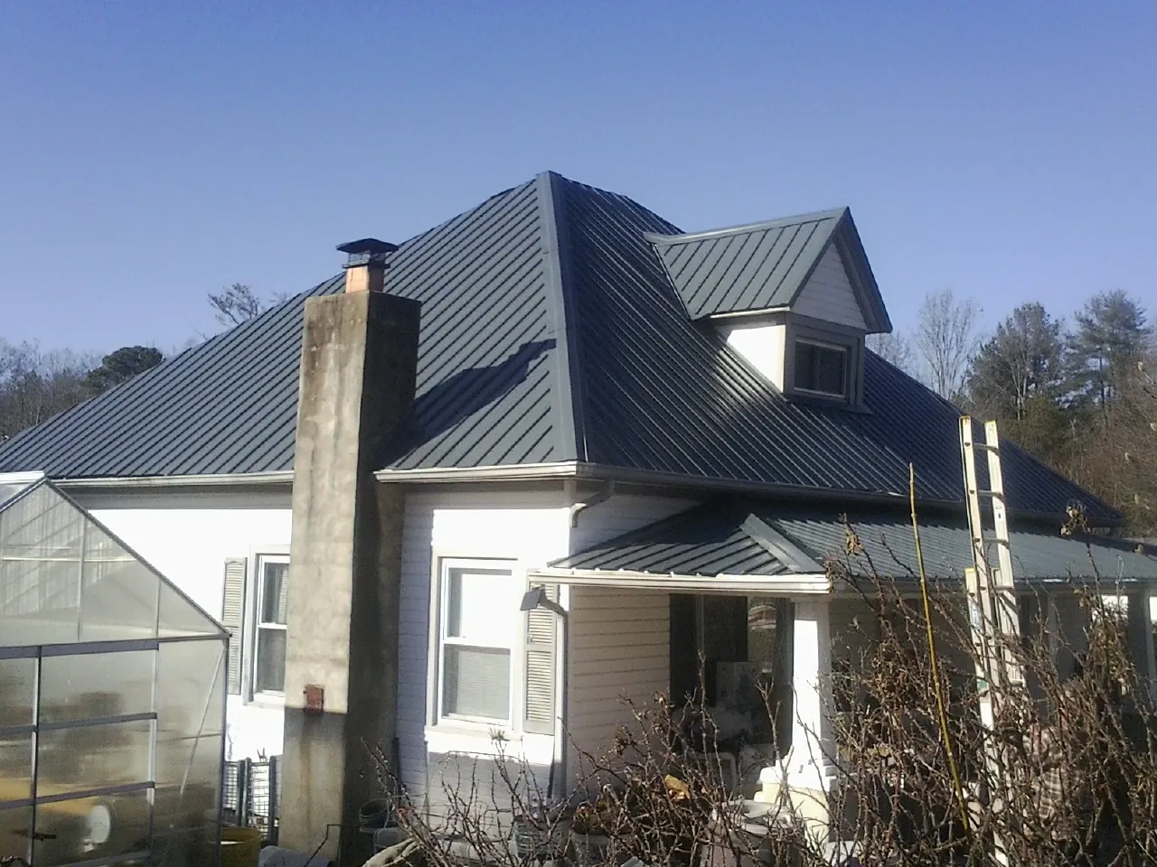 Dark blue standing seam metal roof on a white farmhouse with dormer — Slate & Tile Roof Repair by Roofing Brothers in Drexel Hill