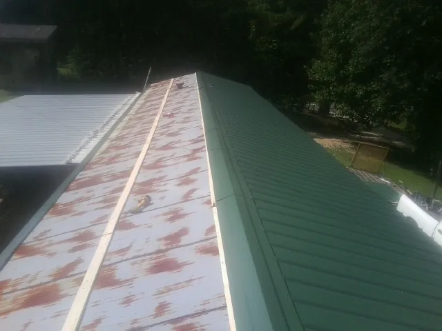 Old rusted panels beside newly installed green metal roofing — Wind Damage Roof Repair by Roofing Brothers in Drexel Hill