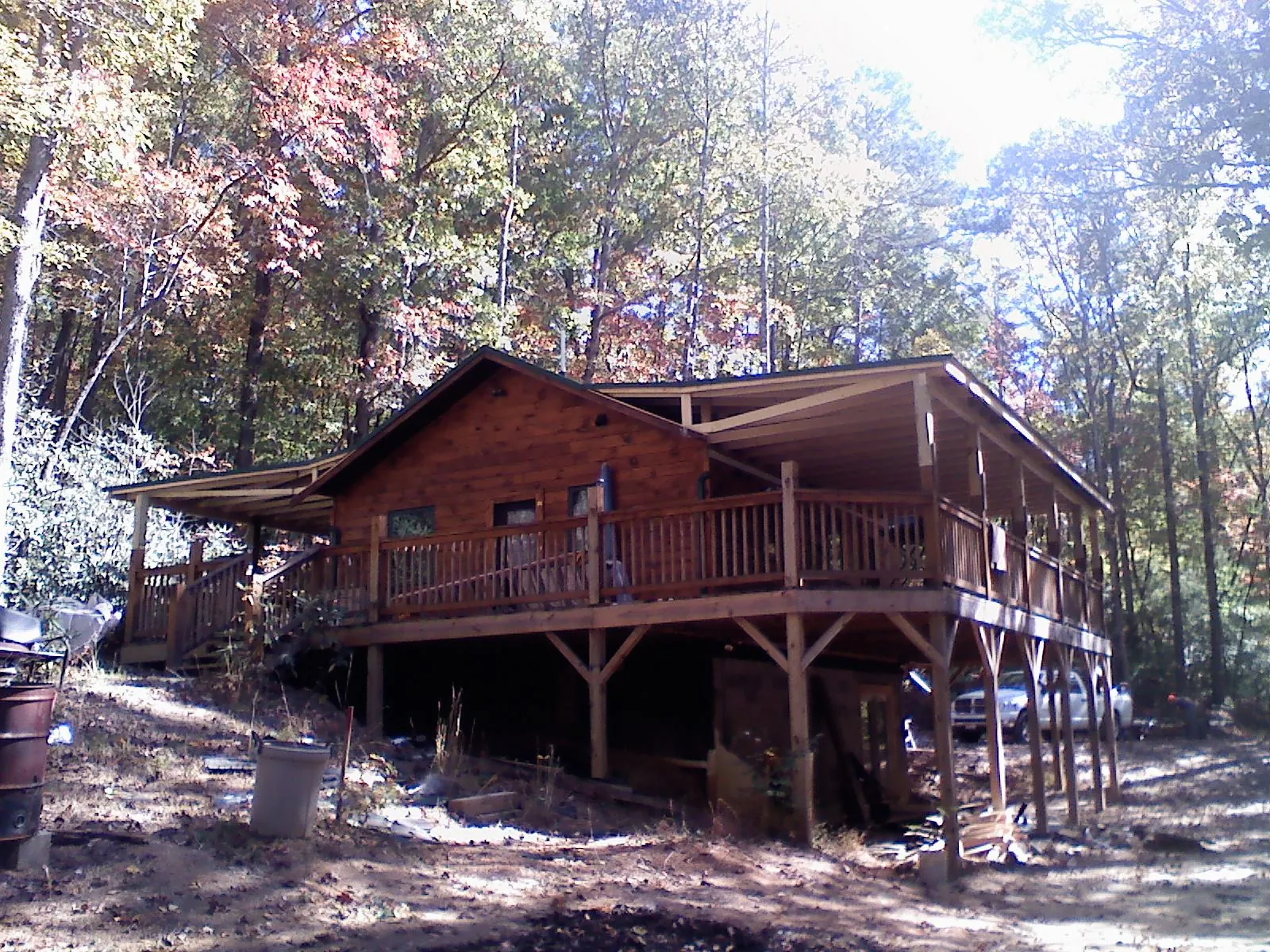 Log cabin with a wraparound porch and metal roof in the fall in Drexel Hill