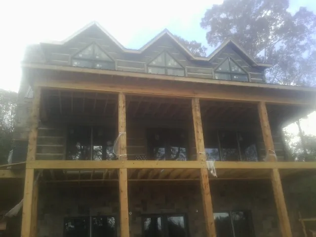 Dormers and porch framing on a large log home under construction — Roof Coating work by our crew in Drexel Hill