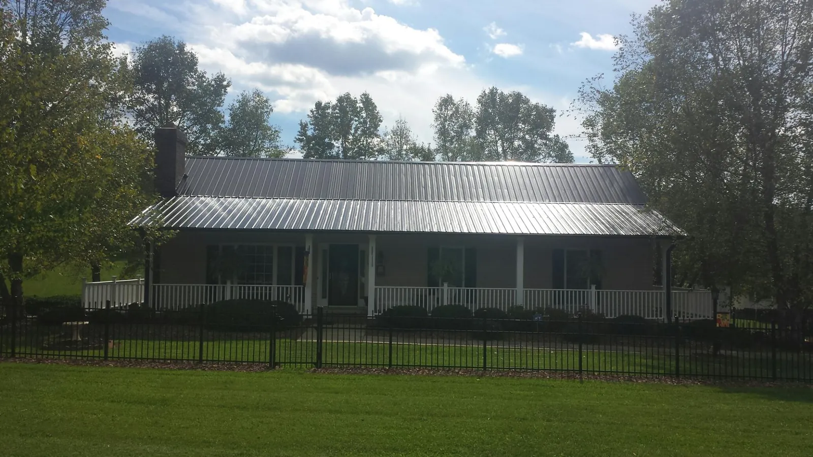 Gray metal roof on a brick ranch with a full width front porch — Gutter Guard Installation work by our crew in Drexel Hill
