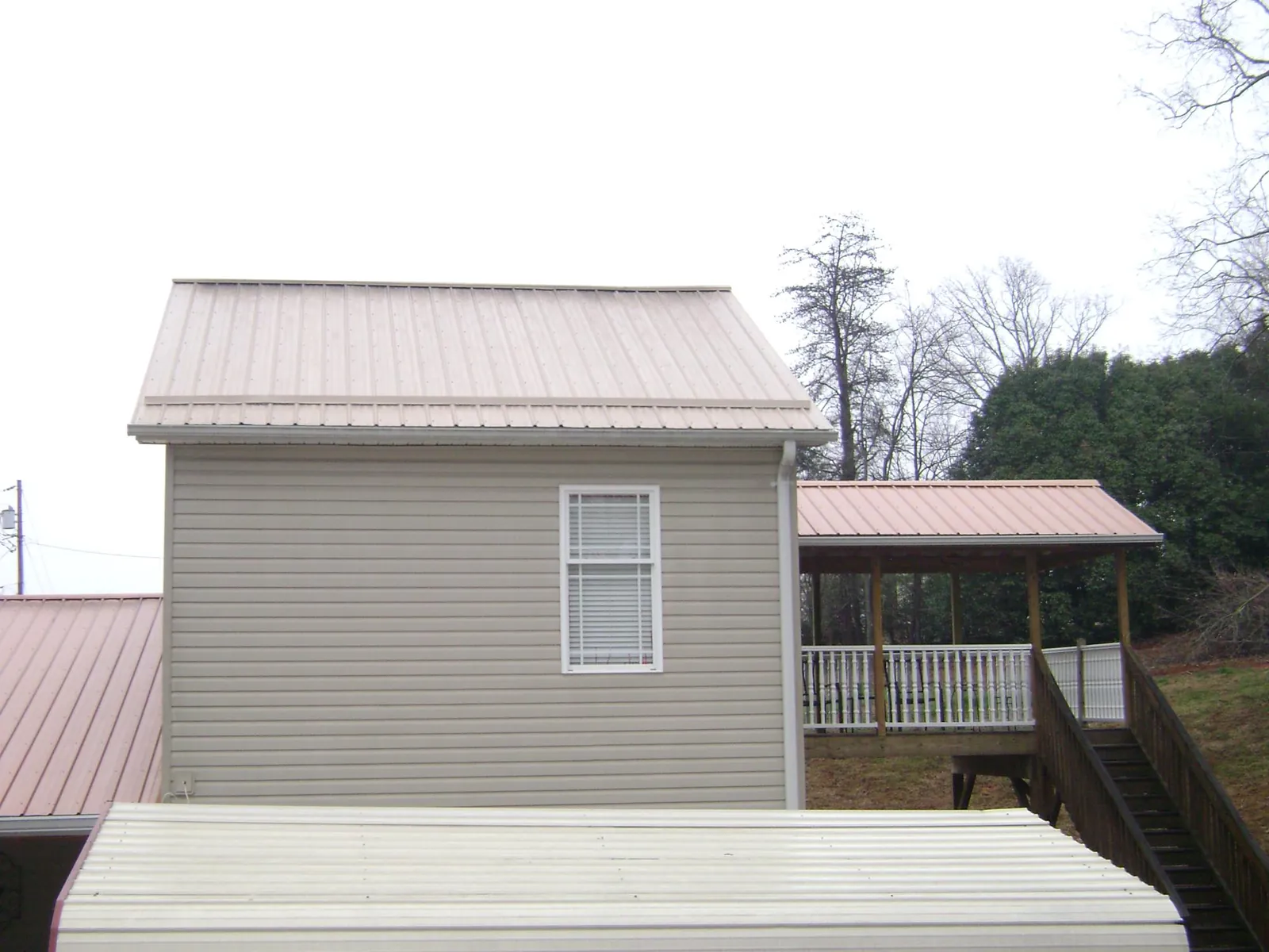 Tan metal roofs on a two story addition and attached porch, from a Roof Replacement job in Drexel Hill