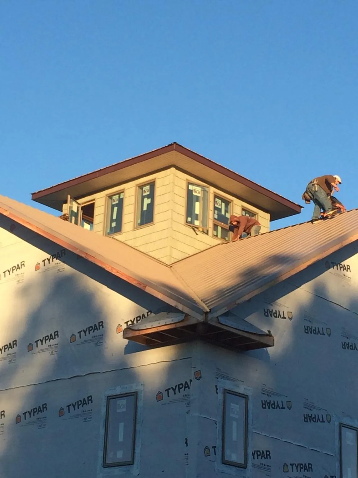 Roofers working around a rooftop cupola on a new metal roof at sunset — Roof Waterproofing in Drexel Hill by Roofing Brothers
